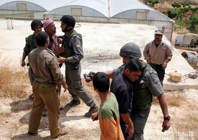 Palestinians argue with Israeli border guards as Israeli army machinery destroy a water reservoir used by Palestinian farmers in Hebron, in the Israeli-occupied West Bank, on June 14,2011. Photo by Najeh Hahlamoun.