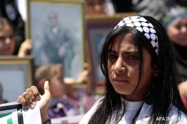 A Palestinian girl holds banners calling for the release of prisoners from Israeli jails, outside the Red Cross offices in the West Bank city of Hebron on June 15, 2011. Photo by Najeh Hashlamoun