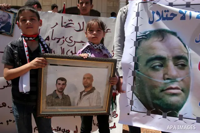 Palestinians hold pictures and banners of their jailed relatives during a protest calling for the release of prisoners from Israeli jails, outside the Red Cross offices in the West Bank city of Hebron on June 15, 2011. P...