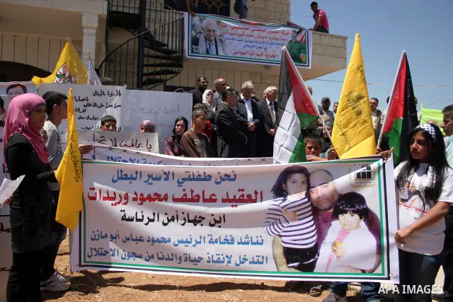Palestinians hold pictures and banners of their jailed relatives during a protest calling for the release of prisoners from Israeli jails, outside the Red Cross offices in the West Bank city of Hebron on June 15, 2011. P...