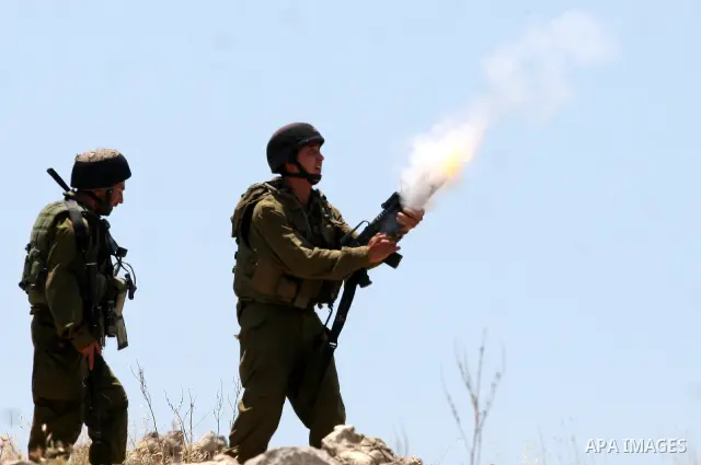 An Israeli soldier fires tear gas canister toward Palestinian protestors as residents from the village of Deir Qadis near Ramallah tried to prevent Israeli bulldozers from progressing towards their land during a demonstr...