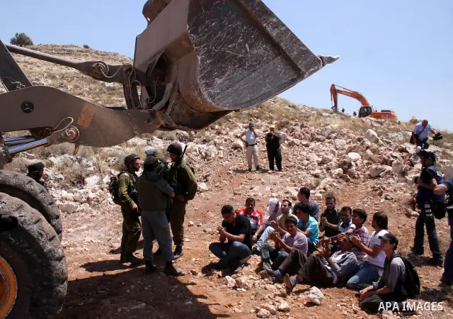 Palestinians from the village of Deir Qadis near Ramallah try to prevent Israeli bulldozers from progressing towards their land during a demonstration against the expansion of nearby settlements on June 15, 2011, in the...
