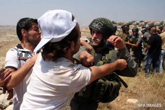 An Israeli soldier scuffles with a Palestinian protestor as residents from the village of Deir Qadis near Ramallah tried to prevent Israeli bulldozers from progressing towards their land during a demonstration against th...