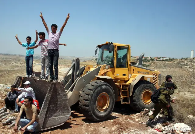 Palestinians from the village of Deir Qadis near Ramallah try to prevent Israeli bulldozers from progressing towards their land during a demonstration against the expansion of nearby settlements on June 15, 2011, in the...