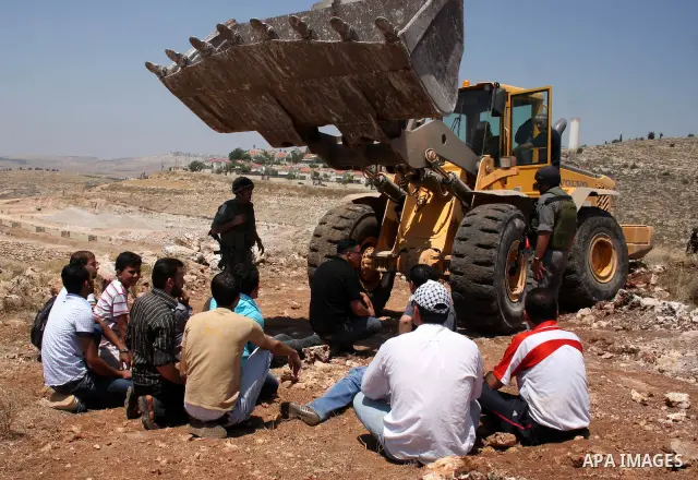 Palestinians from the village of Deir Qadis near Ramallah try to prevent Israeli bulldozers from progressing towards their land during a demonstration against the expansion of nearby settlements on June 15, 2011, in the...