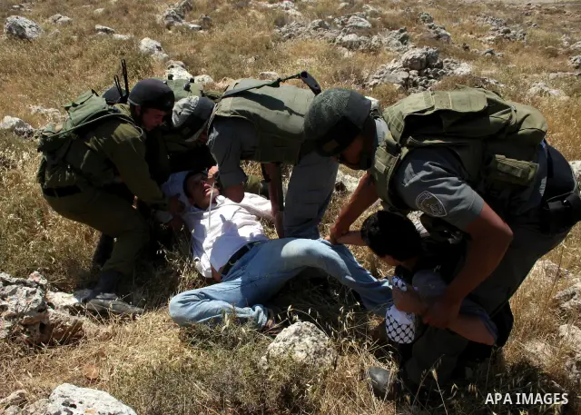 Israeli soldiers arrest a Palestinian protestor as residents from the village of Deir Qadis near Ramallah tried to prevent Israeli bulldozers from progressing towards their land during a demonstration against the expansi...