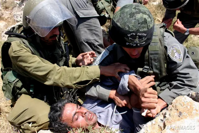 Israeli soldiers arrest a Palestinian protestor as residents from the village of Deir Qadis near Ramallah tried to prevent Israeli bulldozers from progressing towards their land during a demonstration against the expansi...