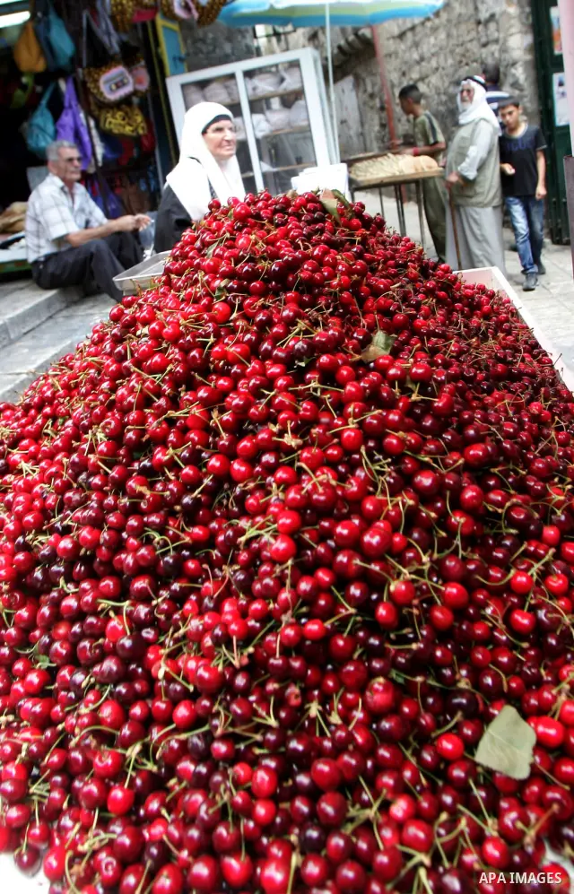 A Palestinian woman walks past a pile of cherry at the main market in Jerusalem's old city on Jun 15,2011. Photo by Mahfouz Abu Turk