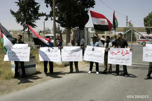 Palestinians hold their national flags and the Egyptian flags and banners during a rally in front of the Rafah border crossing in the southern Gaza Strip on June 16, 2011, demanding it to be open permanently and without...