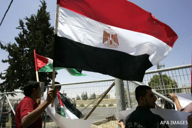 Palestinians hold their national flags and the Egyptian flags and banners during a rally in front of the Rafah border crossing in the southern Gaza Strip on June 16, 2011, demanding it to be open permanently and without...
