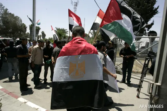 Palestinians hold their national flags and the Egyptian flags and banners during a rally in front of the Rafah border crossing in the southern Gaza Strip on June 16, 2011, demanding it to be open permanently and without...