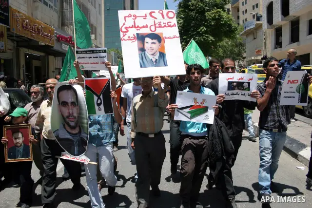 Palestinian Hamas supporters hold up pictures of relatives who were arrested and imprisoned for political reasons by Palestinian Authority security forces, during a protest in the West Bank city of Hebron, on June 16,201...
