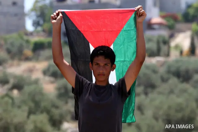 A Palestinian protestor holds up his national flag as residents from the village of Deir Qadis near Ramallah hold a demonstration against the expansion of nearby settlements on June 16, 2011, in the Israeli-occupied West...