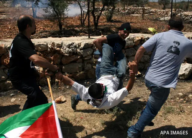 Protestors carry a wounded youth during clashes with Israeli forces following a weekly demonstration against Israel's separation barrier in the Palestinian West Bank village of Bilin on June 17, 2011. Photo by Issam Rima...