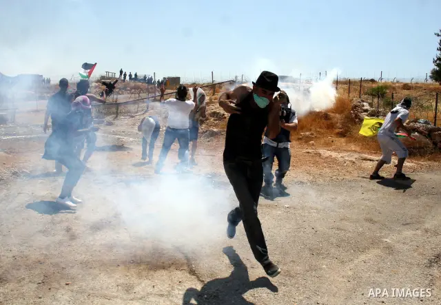 Protestors run amidst tear gas smoke fired by Israeli forces during clashes following a weekly demonstration against Israel's separation barrier in the Palestinian West Bank village of Bilin on June 17, 2011. Photo by Is...