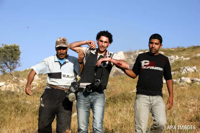 Palestinians evacuate a wounded press photographer during a demonstration against the expansion of Jewish settlements on June 18, 2011 in the village of Iraq Burin, south of the northern West Bank city Nablus. Photo by N...