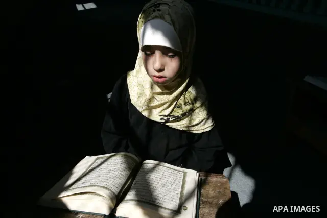 A Palestinian girl reads the Koran at a summer camp for the study of Islam's holy book organised by the Islamist movement Hamas in Rafah in the southern of Gaza Strip on June 19, 2011. Photo by Abed Rahim Khatib
