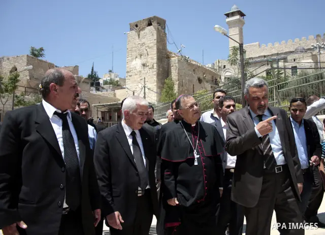 The head of the Roman Catholic Church in the Holy Land, the Latin Patriarch of Jerusalem Fuad Twal walks among Palestinian officials near the Ibrahimi Mosque, or Tomb of the Patriarchs, during a visit to the divided West...