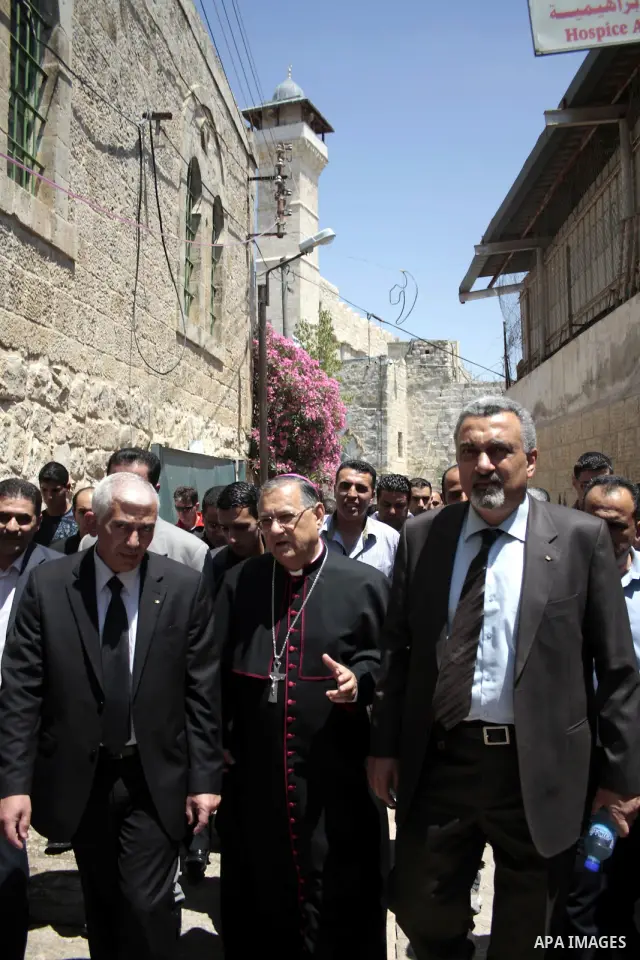 The head of the Roman Catholic Church in the Holy Land, the Latin Patriarch of Jerusalem Fuad Twal walks among Palestinian officials near the Ibrahimi Mosque, or Tomb of the Patriarchs, during a visit to the divided West...