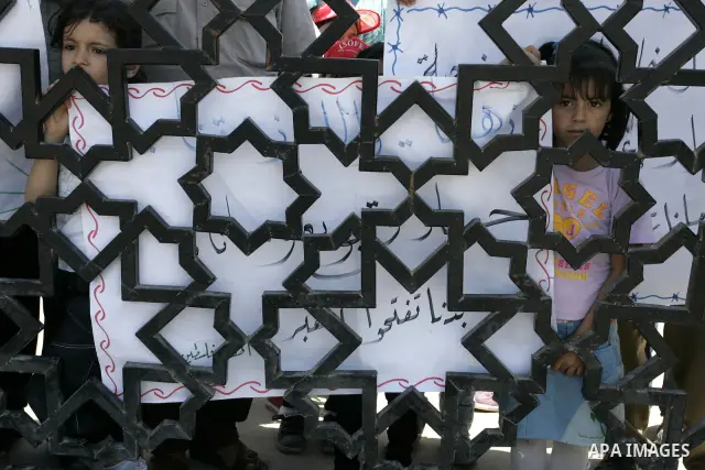 Palestinian children hold banners during a rally in front of the Rafah border crossing with Egypt in the southern Gaza Strip on June 21, 2011, demanding it to be open permanently and without restrictions or conditions on...