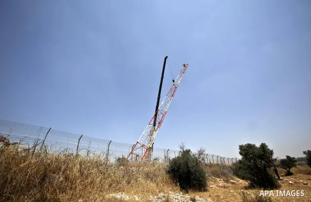Israeli army machinery dismantle on June 22, 2011 a section of Israel's separation fence in the West Bank village of Bilin following a decision by the Israeli Supreme Court four years ago. Photo by Issam Rimawi