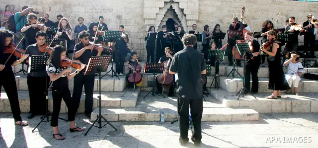 Palestinians and foreigners play the violin in front of the Damascus Gate in Jerusalem's old city on Jun 22,2011. Photo by Mahfouz Abu Turk