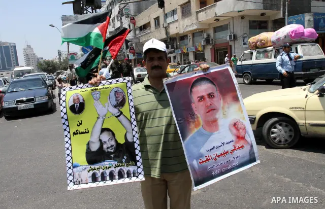 A Palestinian man holding pictures of their jailed relatives attend a protest calling for the release of Palestinian prisoners from Israeli jails , in Gaza City on June 23, 2011, as 7,500 Palestinian prisoners are held i...