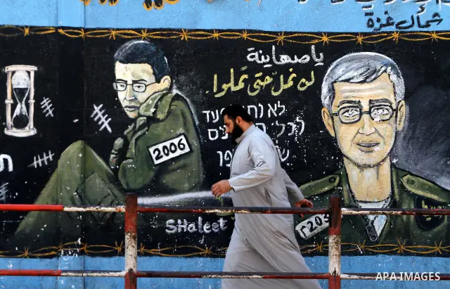 A Palestinian man walks past a mural depicting captured Israeli soldier Gilad Shalit in Jabalya in the northern Gaza Strip June 23, 2011. The Red Cross called on Hamas on Thursday to provide proof that Shalit, captured b...