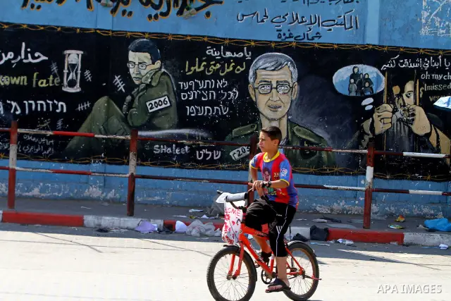 A Palestinian boy rides his bike past a mural depicting captured Israeli soldier Gilad Shalit in Jabalya in the northern Gaza Strip June 23, 2011. The Red Cross called on Hamas on Thursday to provide proof that Shalit, c...