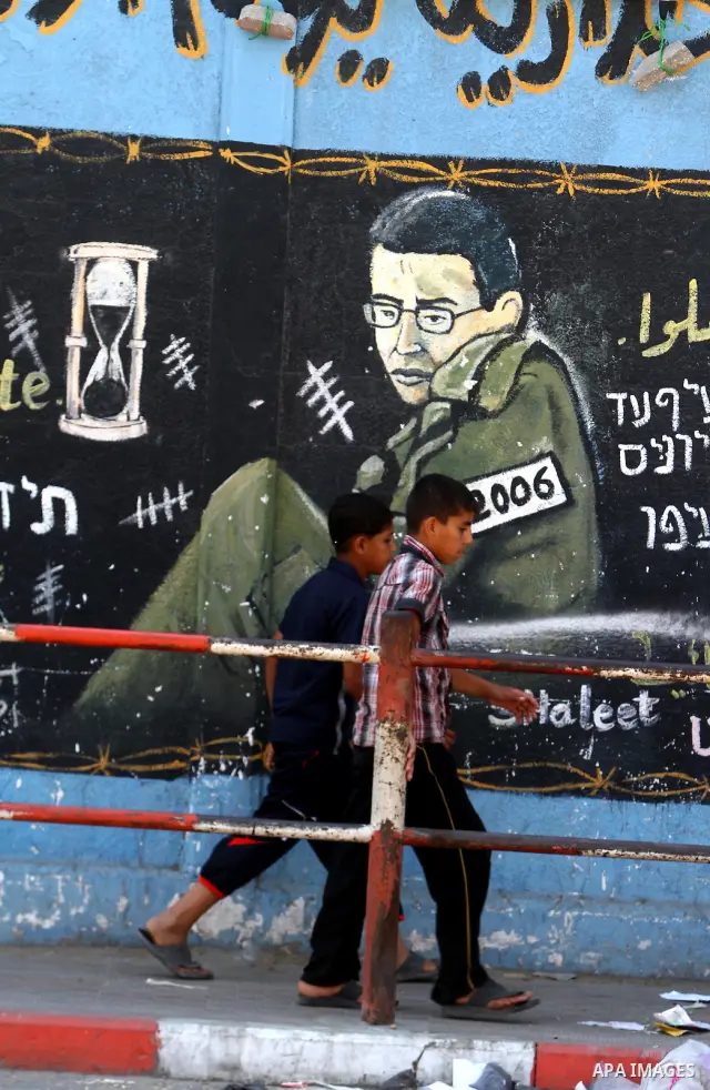 Palestinian boys walk past a mural depicting captured Israeli soldier Gilad Shalit in Jabalya in the northern Gaza Strip June 23, 2011. The Red Cross called on Hamas on Thursday to provide proof that Shalit, captured by...
