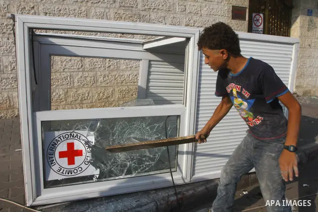 A Palestinian boy destroys the guard post outside the building housing the offices of the International Committee of the Red Cross (ICRC) as dozens of angry protesters demonstrated outside the premises of the ICRC in Gaz...