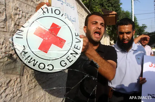 A Palestinian man holds the broken glass sign of the International Committee of the Red Cross (ICRC) as dozens of angry protesters demonstrated outside the premises of the ICRC in Gaza City on June 23, 2011 against a cal...