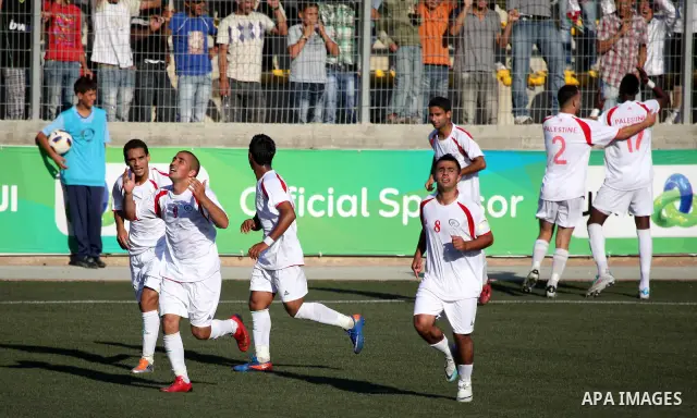 Palestinian team players celebrate after scoring a goal against the Bahraini national team during their 2012 Olympic qualifying football match in the West Bank town of Al-Ram, near Ramallah, on June 23, 2011. Photo by Is...