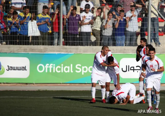 Palestinian team players celebrate after scoring a goal against the Bahraini national team during their 2012 Olympic qualifying football match in the West Bank town of Al-Ram, near Ramallah, on June 23, 2011. Photo by Is...