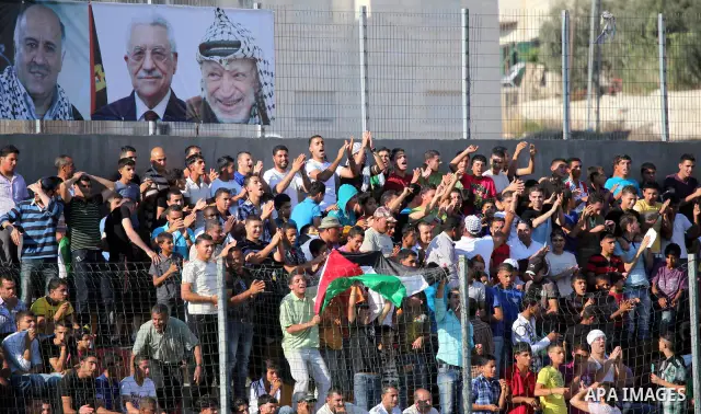 Palestinian fans attend a football match between their national team and Bahrain team during their 2012 Olympic qualifying football match in the West Bank town of Al-Ram, near Ramallah, on June 23, 2011. Photo by Issam R...