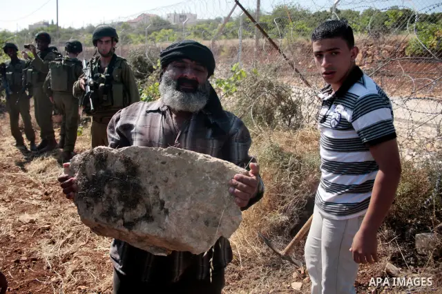 Israeli soldiers stand guards as protesters help a Palestinian farmer in his land on Jun 24, 2011 during a demonstration by foreign, Israeli and Palestinian activists against the Jewish settlement of Karmei Tzur near the...