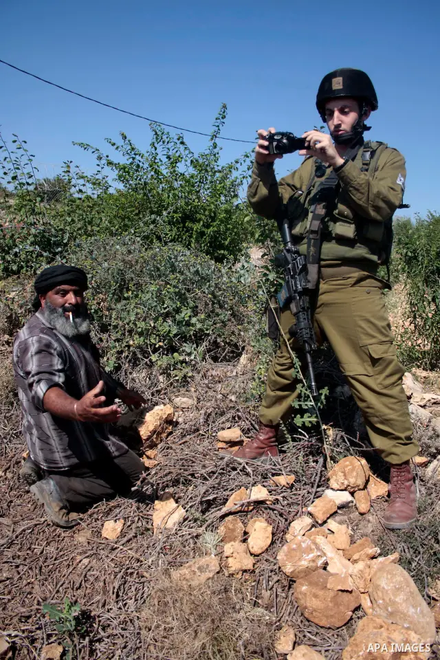 Israeli soldiers stand guards as protesters help a Palestinian farmer in his land on Jun 24, 2011 during a demonstration by foreign, Israeli and Palestinian activists against the Jewish settlement of Karmei Tzur near the...