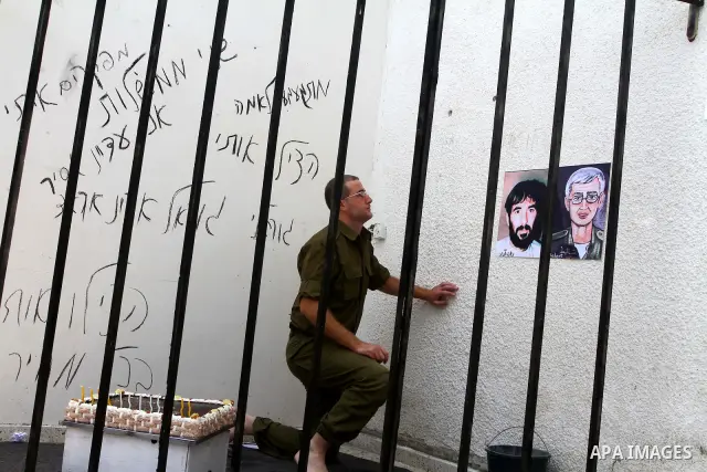 A Palestinian playing the role of Israeli soldier Gilad Shalit stands in a cage to mark the fifth anniversary of his capture by Palestinian militants, in Jabalya in the northern Gaza Strip June 25, 2011. The Hebrew writi...