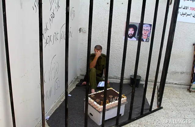 A Palestinian playing the role of Israeli soldier Gilad Shalit stands in a cage to mark the fifth anniversary of his capture by Palestinian militants, in Jabalya in the northern Gaza Strip June 25, 2011. The Hebrew writi...