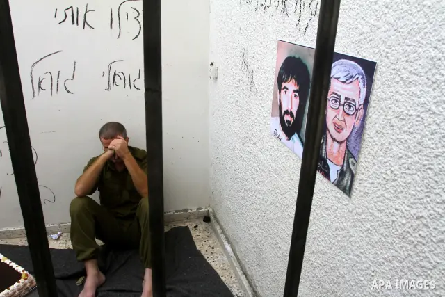 A Palestinian playing the role of Israeli soldier Gilad Shalit stands in a cage to mark the fifth anniversary of his capture by Palestinian militants, in Jabalya in the northern Gaza Strip June 25, 2011. The Hebrew writi...