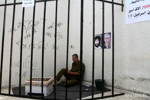 A Palestinian playing the role of Israeli soldier Gilad Shalit stands in a cage to mark the fifth anniversary of his capture by Palestinian militants, in Jabalya in the northern Gaza Strip June 25, 2011. The Hebrew writi...