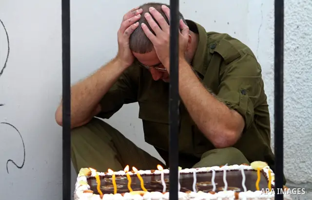 A Palestinian playing the role of Israeli soldier Gilad Shalit stands in a cage to mark the fifth anniversary of his capture by Palestinian militants, in Jabalya in the northern Gaza Strip June 25, 2011. The Hebrew writi...