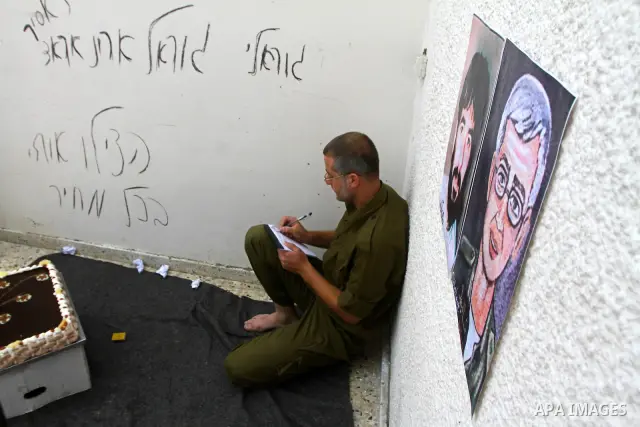A Palestinian playing the role of Israeli soldier Gilad Shalit stands in a cage to mark the fifth anniversary of his capture by Palestinian militants, in Jabalya in the northern Gaza Strip June 25, 2011. The Hebrew writi...