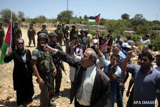 Israeli soldiers scuffle with Palestinian, Israeli and foreign activists during a demonstration against the demolishing of farm land to be used in the construction of Jewish settlements near the existing Israeli settleme...