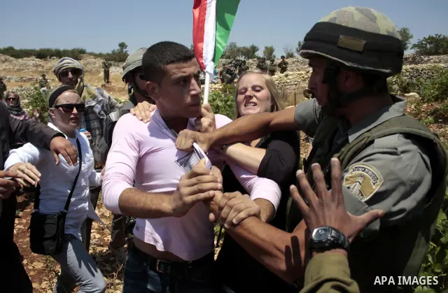 An Israeli soldier detains a Palestinian protester during a demonstration against the demolishing of farm land to be used in the construction of Jewish settlements near the existing Israeli settlement of Karmi Tsor near...