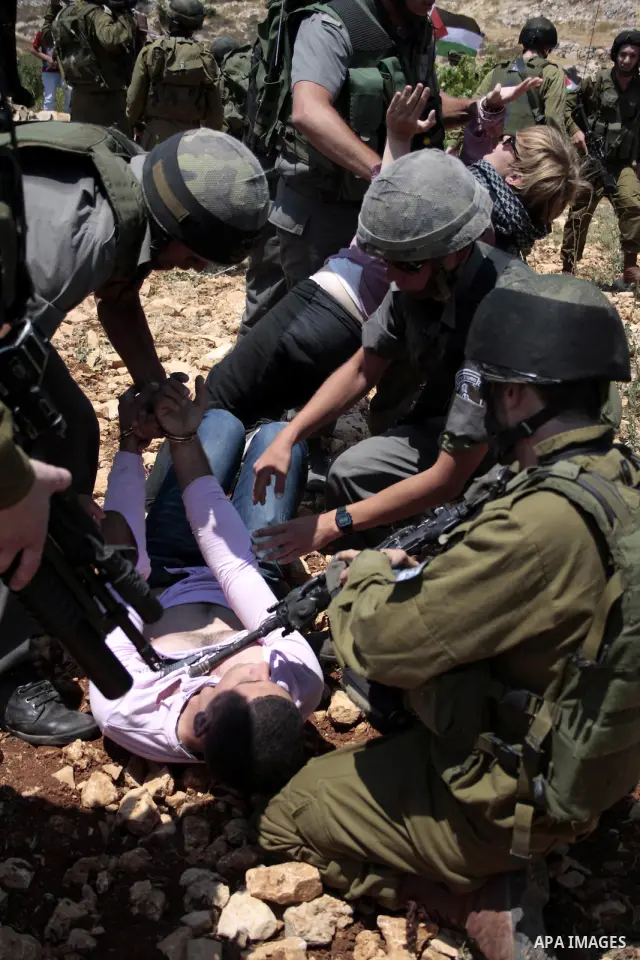Israeli soldiers detain a Palestinian protester during a demonstration against the demolishing of farm land to be used in the construction of Jewish settlements near the existing Israeli settlement of Karmi Tsor near the...