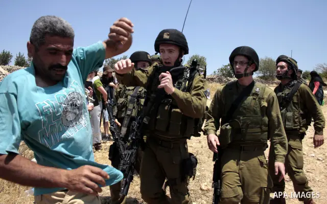 Israeli soldiers scuffles with a Palestinian protester during a demonstration against the demolishing of farm land to be used in the construction of Jewish settlements near the existing Israeli settlement of Karmi Tsor n...