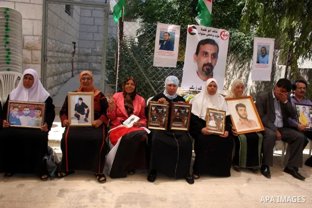 Palestinians hold pictures of relatives jailed in Israel during a protest against Israeli Prime Minister Benjamin Netanyahu's decision to worsen the prisoners holding conditions on Jun 26,2011, outside the International...