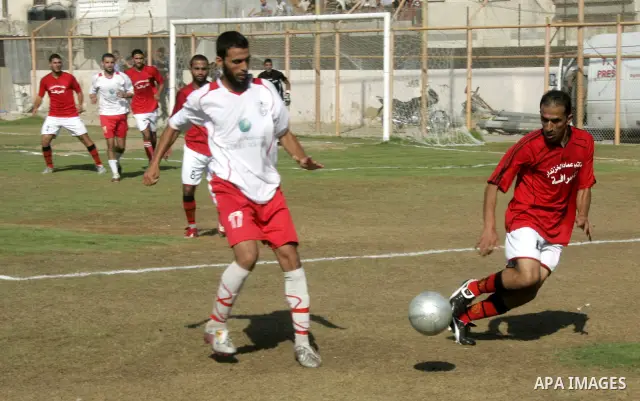 Palestinian football players challenge for the ball during a football match between Khan Yunis Youth club (red shirt) and Rafah Collective club (white shirt) on Jun 27, 2011 in the southern Gaza Strip town of Rafah. Phot...