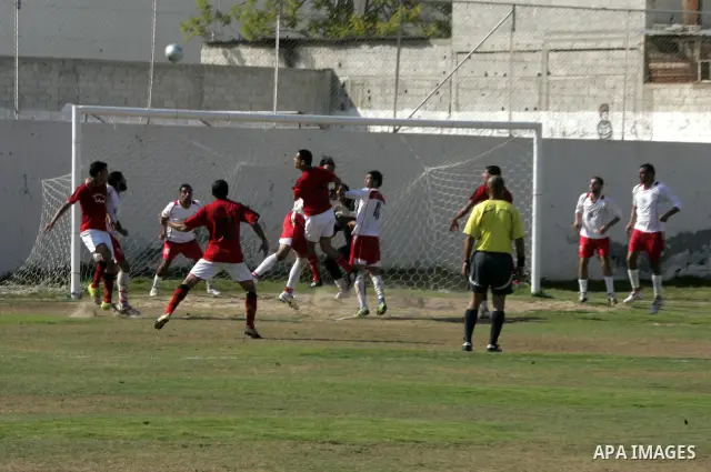 Palestinian football players challenge for the ball during a football match between Khan Yunis Youth club (red shirt) and Rafah Collective club (white shirt) on Jun 27, 2011 in the southern Gaza Strip town of Rafah. Phot...